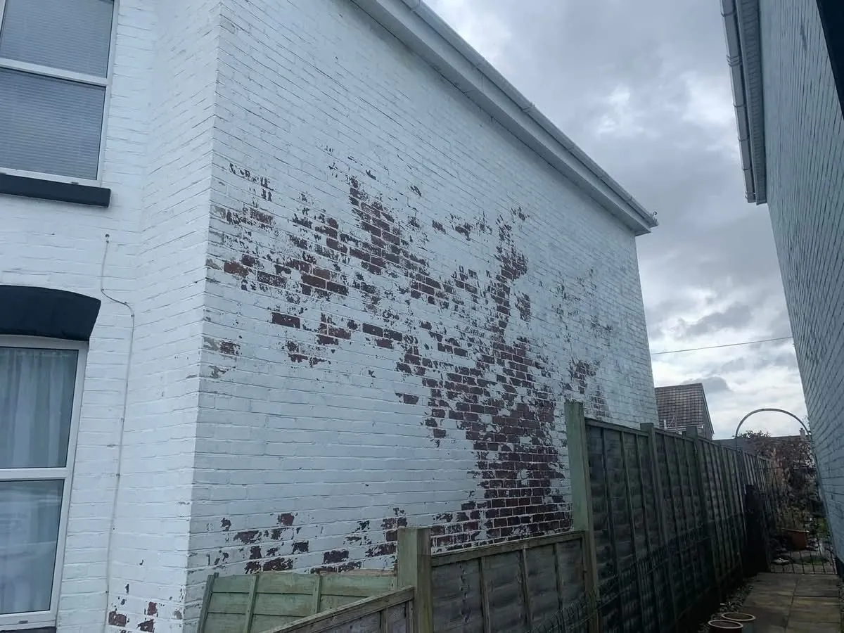 Peeling paint on a brick wall before redecoration in Exeter